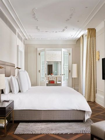 Elegantes Zimmer mit luxuriösem Bett, dekorativer Decke und Zugang zum Badezimmer.