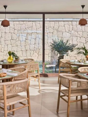 Heller Restaurantbereich mit Holzmöbeln und Blick auf eine Steinmauer.