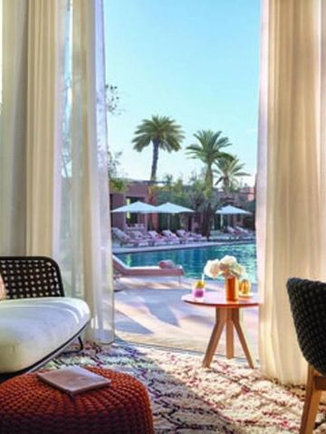 Blick aus dem Hotelzimmer auf den sonnigen Poolbereich mit Palmen