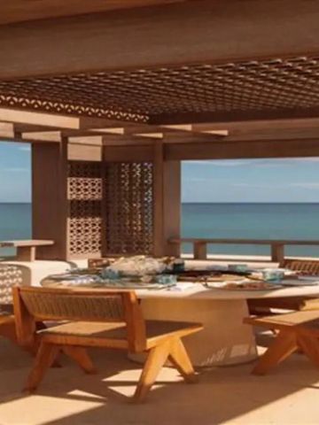 Holzüberdachung mit runden Tisch und Stühlen am Strand