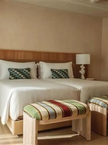 Doppelzimmer mit zwei Betten, dekorativen Sitzbänken und modernen Lampen