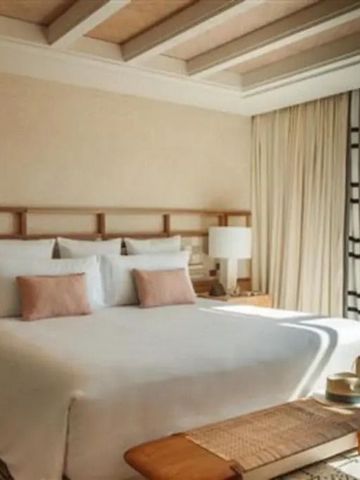 Komfortables Schlafzimmer mit Meerblick und breitem Bett. Helle Vorhänge