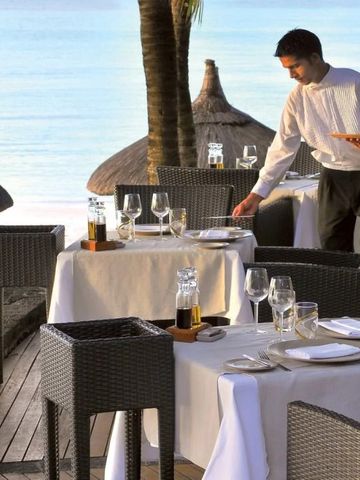 Kellner serviert auf einer Terrasse mit Meerblick gedeckt mit weißen Tischdecken