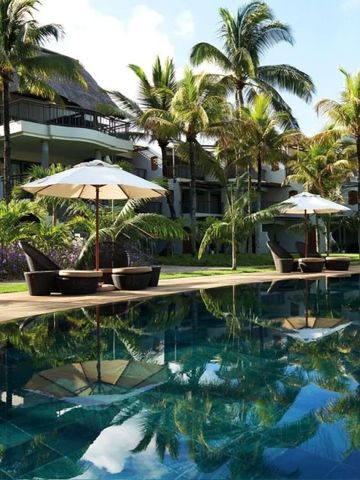 Luxuriöser Poolbereich mit Palmen und Sonnenschirmen vor Hotelgebäude