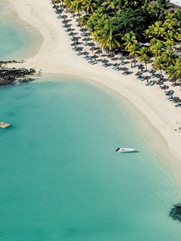 Weißer Sandstrand mit türkisfarbenem Wasser und Liegestühlen unter Palmen