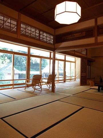 Großer Raum mit Tatami-Matten, Holzverkleidungen und Blick ins Grüne