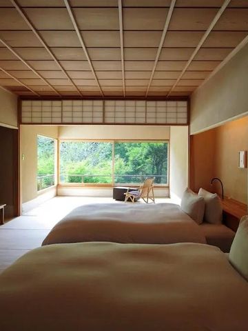 Geräumiges Zimmer mit zwei Betten, großen Fenstern und Blick auf einen grünen Garten.