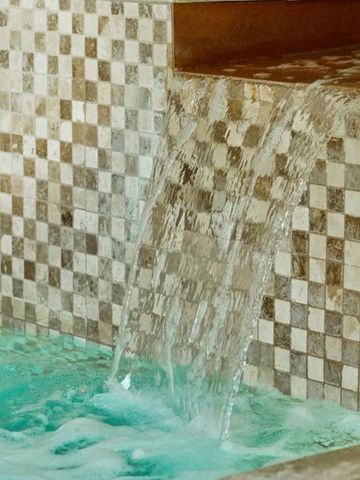 Wasserfall in einem mit Mosaiksteinen gefliesten Spa-Becken