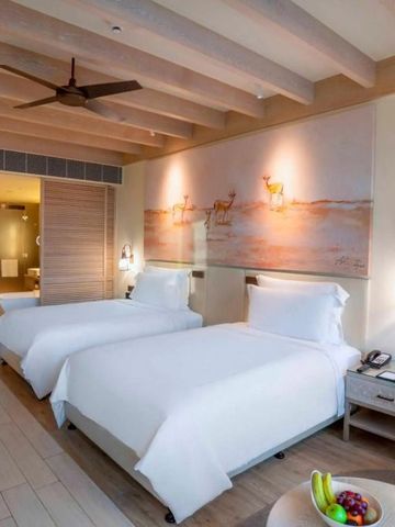 Helles Doppelzimmer mit moderner Kunst an der Wand und Sitzecke.