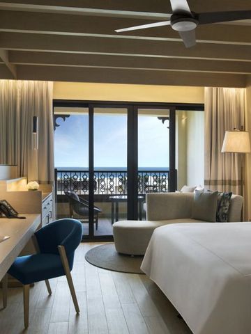 Großes Zimmer mit Doppelbett, Schreibtisch und Balkon mit Meerblick.