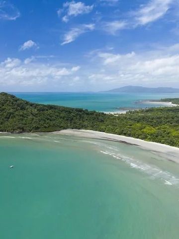 Luftaufnahme einer tropischen Küste mit üppigem Wald und türkisfarbenem Meer.