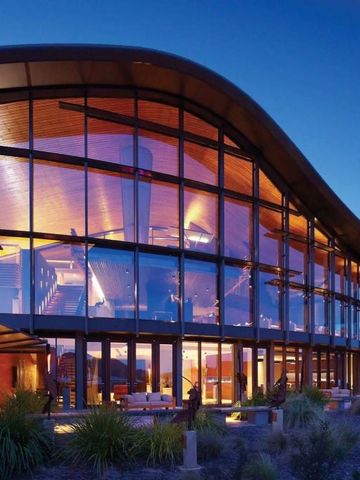 Beeindruckende Glasfassade eines architektonisch modernen Gebäudes bei Dämmerung