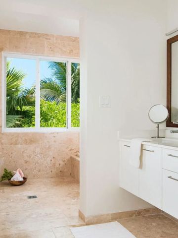 Helles Badezimmer mit großer Fensterfront und Blick auf tropische Pflanzen