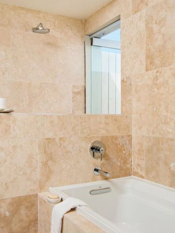 Modernes Badezimmer mit beiger Steinverkleidung und Badewanne