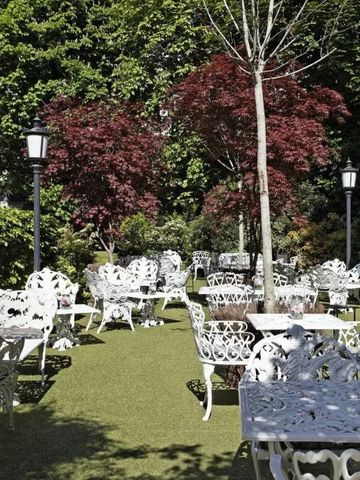 Charmante Gartenanlage mit weißen schmiedeeisernen Möbeln und üppigem Grün