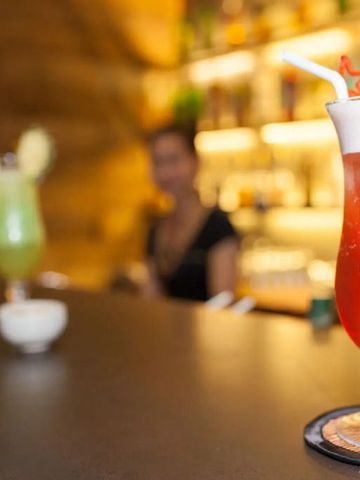 Bunte Cocktails auf Bar mit beleuchtetem Hintergrund