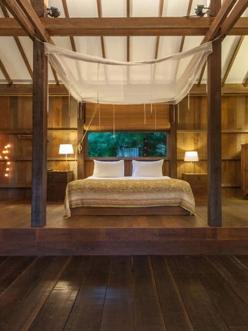 Holzinterieur eines Zimmers mit Himmelbett und Lampe