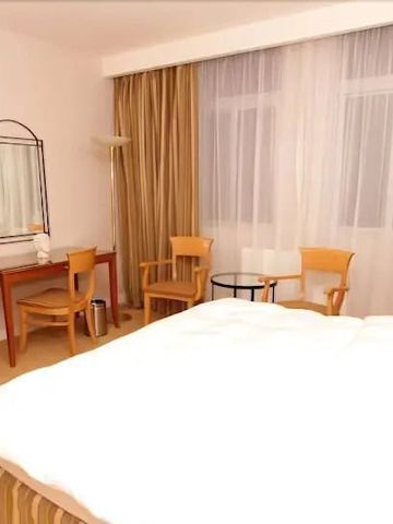 Helles Hotelzimmer mit Doppelbett und Arbeitsbereich