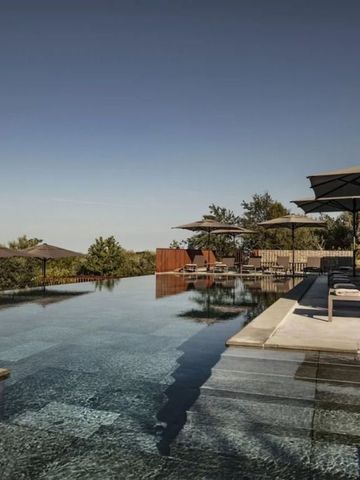 Infinity Pool mit Sonnenschirmen und Aussicht auf die umliegende Landschaft