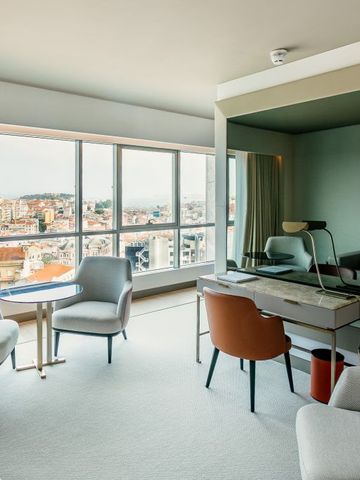 Suite mit großem Fenster und Stadtblick sowie eleganten Sitzmöbeln