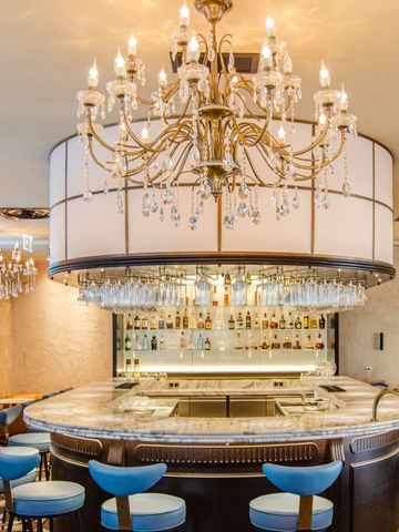 Luxuriöse Bar mit Kristallleuchtern und eleganten Hockern