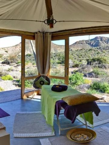 Wellnessraum mit Blick auf Berglandschaft und Massagetisch.