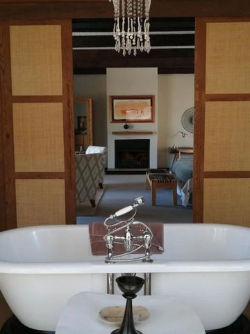 Luxuriöses Badezimmer mit freistehender Badewanne und Kamin im Hintergrund.