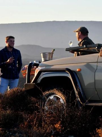 Safari-Erlebnis mit Geländewagen und Gästen in der südafrikanischen Landschaft.