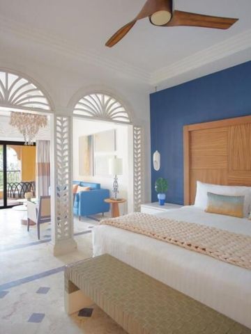 Elegantes Hotelzimmer mit Sitzbereich und Balkon mit Meerblick.