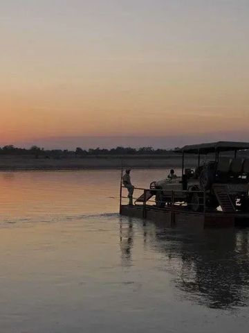 Boot mit Touristen bei Sonnenuntergang auf einem Fluss in der Wildnis