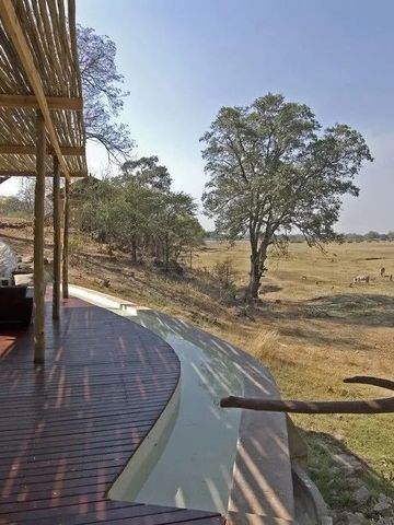 Terrasse mit Blick auf afrikanische Landschaft und Wildtiere bei klarem Himmel