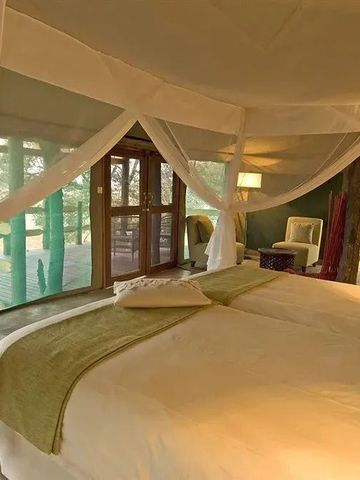 Luxus-Safarizimmer mit Baldachinbett und großen Fenstern