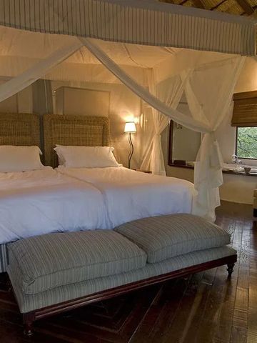 Elegantes Schlafzimmer mit zwei Himmelbetten und dezenter Beleuchtung