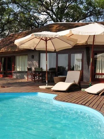 Privater Poolbereich mit Liegestühlen und Sonnenschirmen vor einer Villa