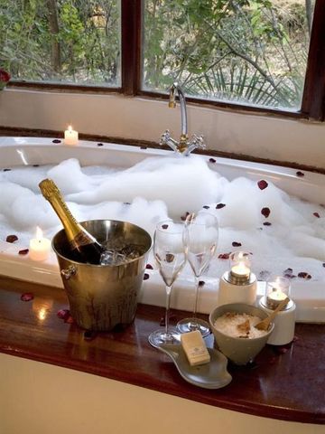 Luxuriöse Badewanne mit Kerzen und Champagner für ein romantisches Ambiente
