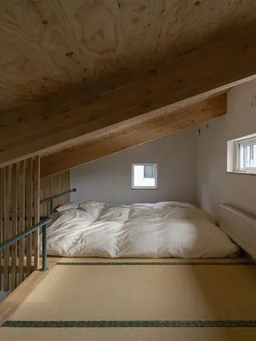 Gemütlicher Schlafbereich unter einem Holzdach mit Tatami-Matte