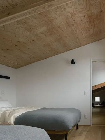 Schlichtes Schlafzimmer mit schrägem Holzplafond und Zugang zu einem Loft