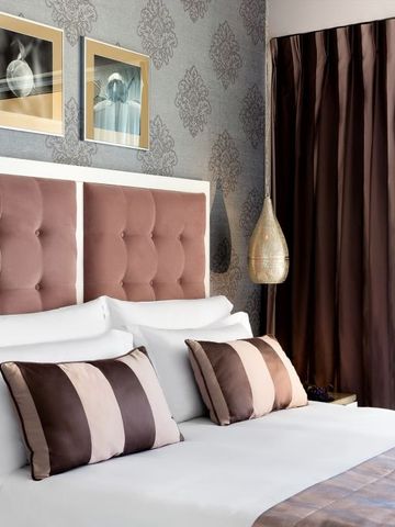 Geräumiges Hotelzimmer mit gepolstertem Kopfteil und luxuriösen Vorhängen