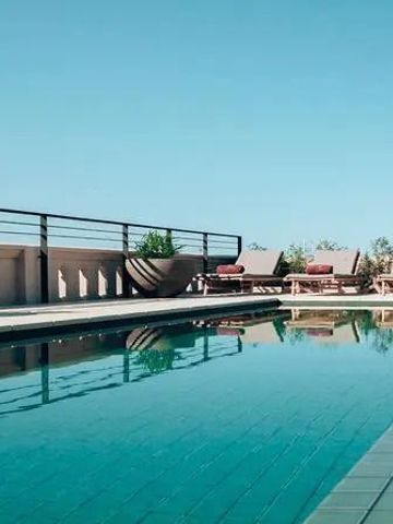 Poolterrasse mit Liegestühlen und klarem Wasser bei blauem Himmel