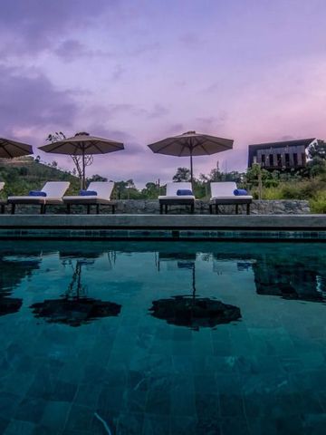 Infinity Pool mit Liegestühlen bei Sonnenuntergang