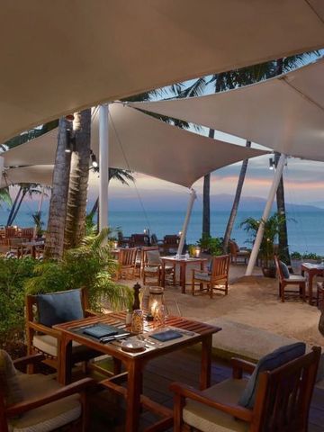 Abendstimmung im Restaurant am Strand mit stilvollen Sitzbereichen unter Segeltüchern.