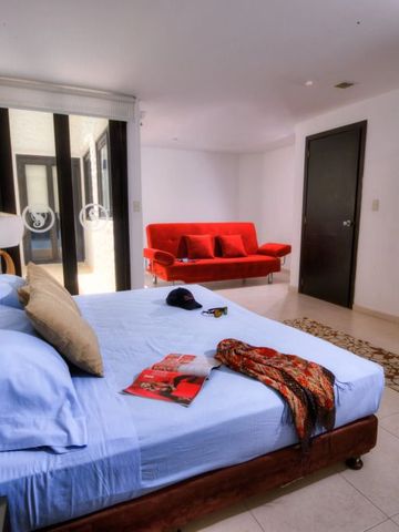 Modern eingerichtetes Hotelzimmer mit Doppelbett und rotem Sofa