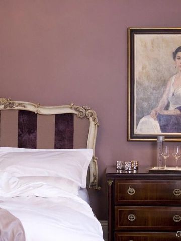 Elegantes Schlafzimmer mit antiken Möbeln und Porträtmalerei an der Wand