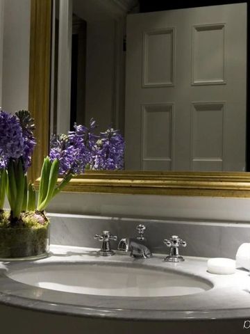 Stilvolles Badezimmer mit lila Blumen und goldgerahmtem Spiegel im Schlosshotel Berlin