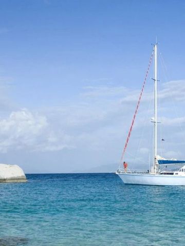 Segelboot auf dem blauen Karibischen Meer mit Felsen im Hintergrund