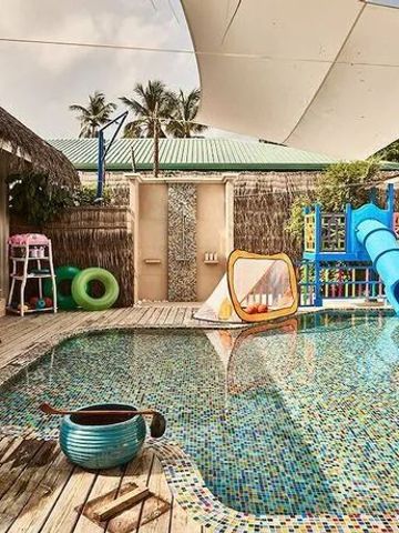 Kinderbereich mit Pool und Spielplatz unter Sonnensegel.