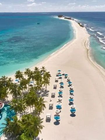 Langer Sandstrand mit Liegestühlen und türkisfarbenem Meer.