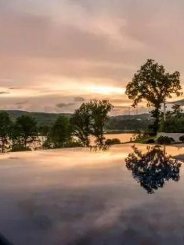 Infinity Pool mit Blick auf die untergehende Sonne und den See