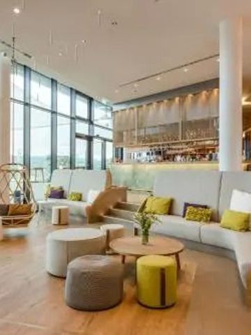 Moderne, einladende Lounge mit großen Fenstern und stilvollen Möbeln