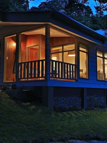 Beleuchtetes Gästehaus bei Nacht mit großen Fenstern